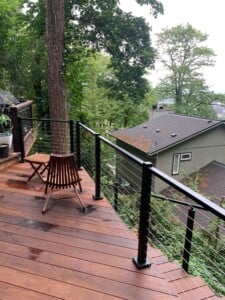 hardwood deck and stairs with cable railings in a forested backyard
